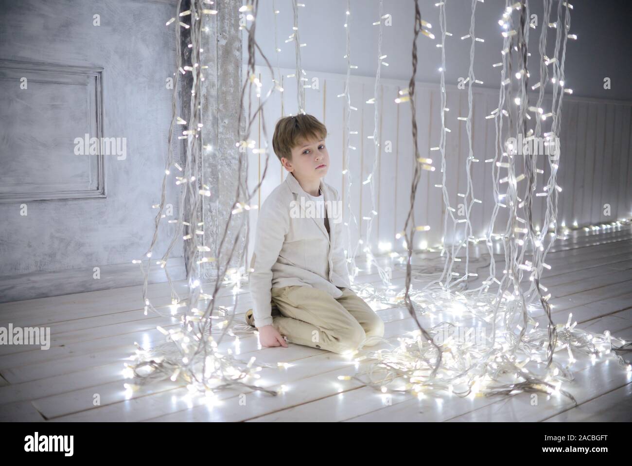 Ein Junge sitzt in den Kreis der hellen Weihnachten Girlanden Stockfoto