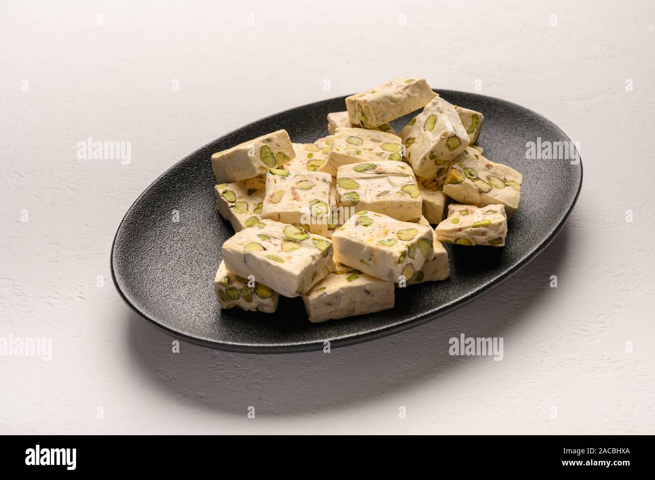 Osten Arabisch nougat Süße mit Pistazien auf eine schwarze Keramikplatte auf einem hellen Hintergrund Stockfoto