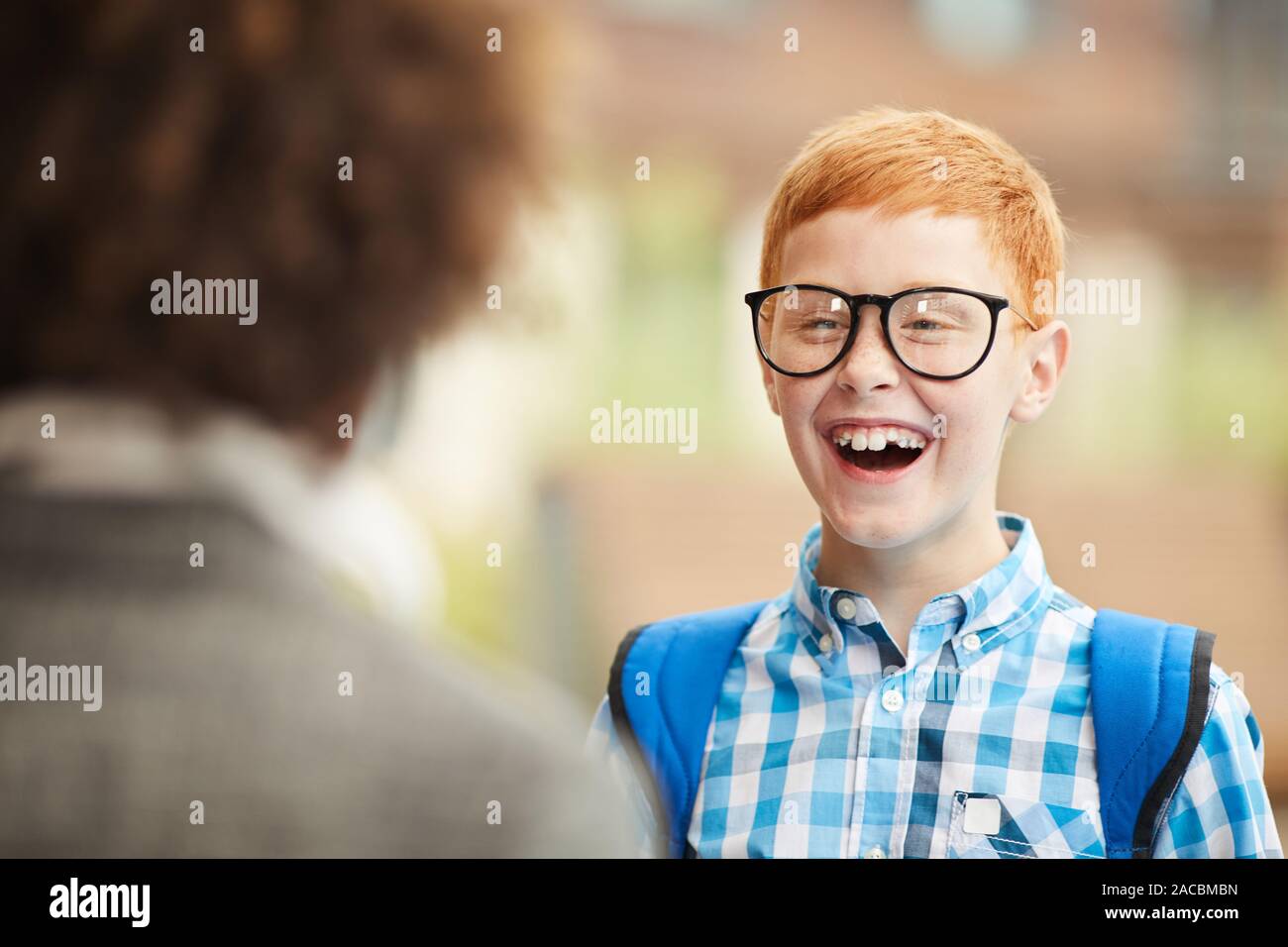 Glückliche Schüler in Brillen lachend im Stehen und im Gespräch mit seinem Freund Stockfoto