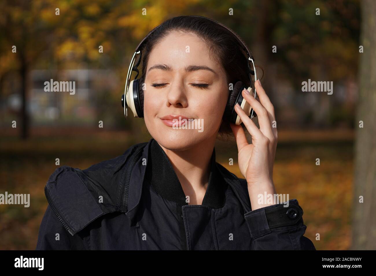 Junge Frau in ihrem 20s Abspielen von Musik mit drahtlosen Kopfhörern im Freien - candid Herbst lifestyle Stockfoto