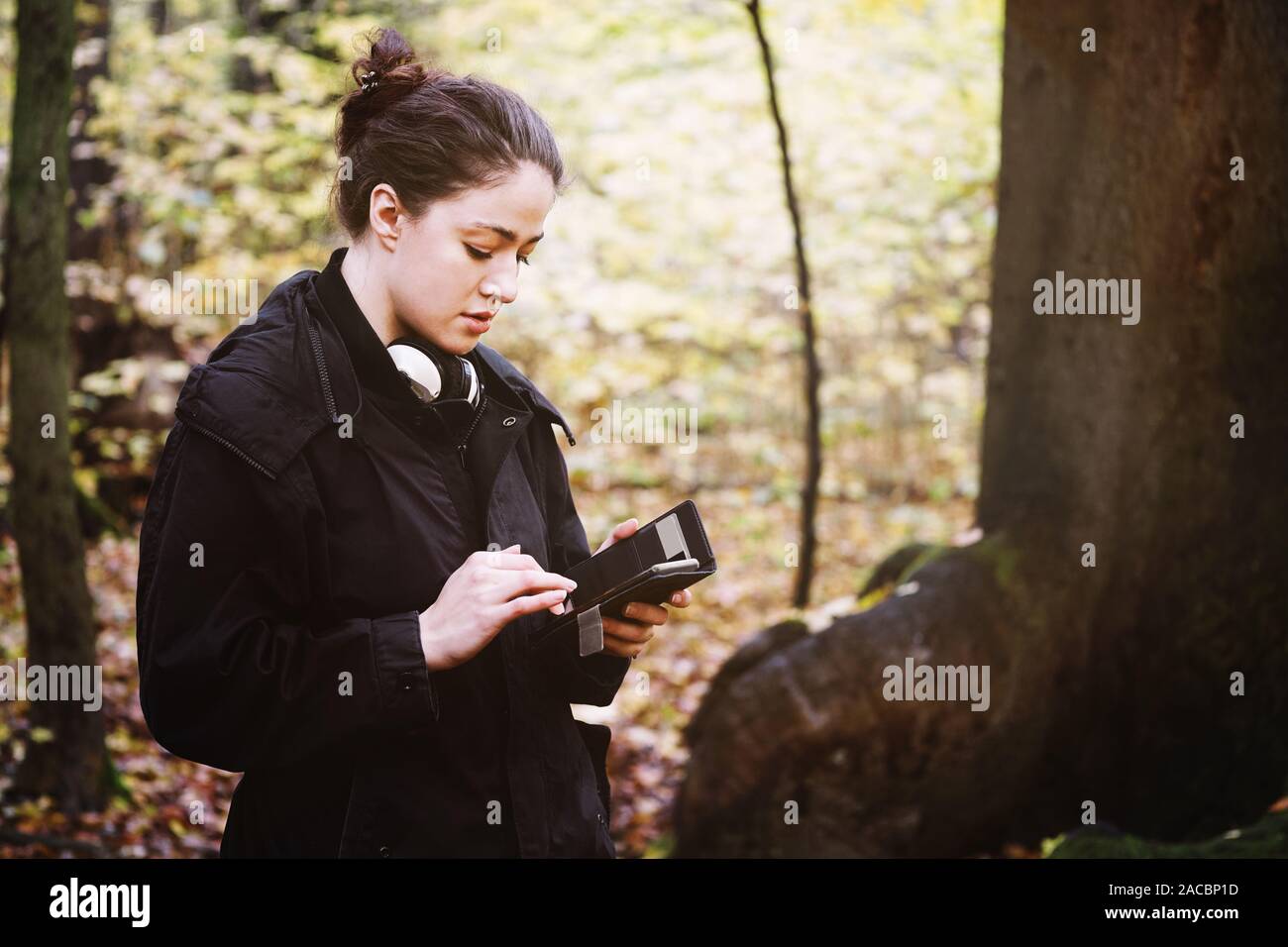 Junge Frau in ihrem 20s mit mobilen Smart Phone draußen im Wald Stockfoto