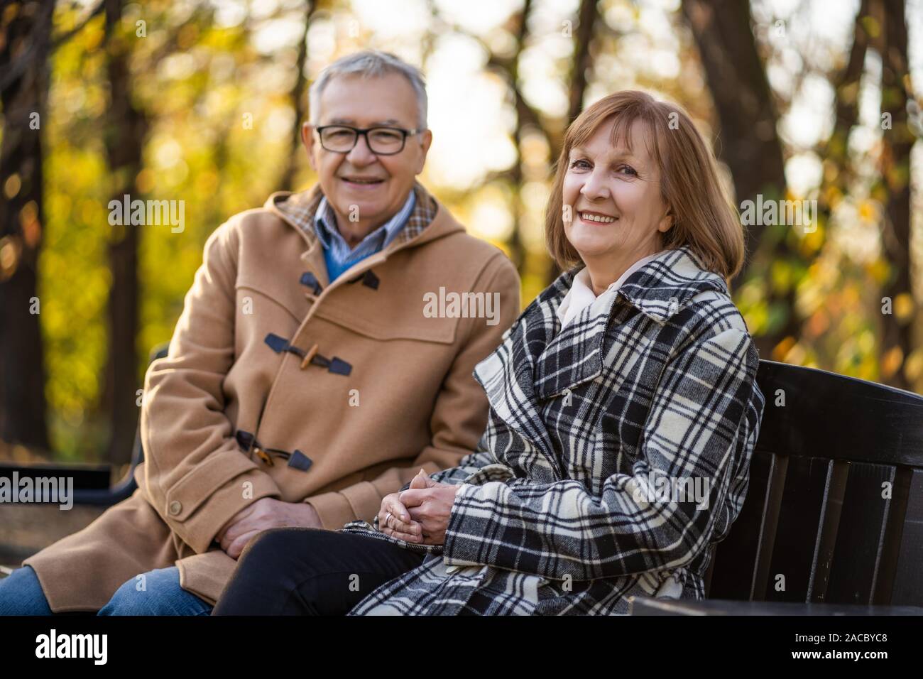 Senior Paar sitzt auf der Bank im Park und genießen Sie den Herbst. Stockfoto