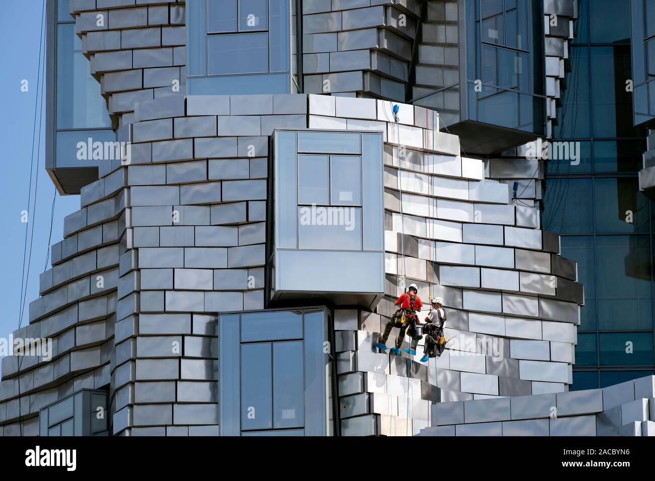Zwei Arbeiter hängend Abseilen/Abseilen während der Reinigung Platten auf Frank Gehry LUMA Foundation Gebäude, Luma kulturelles Zentrum von Arles, Arles, Frankreich Stockfoto