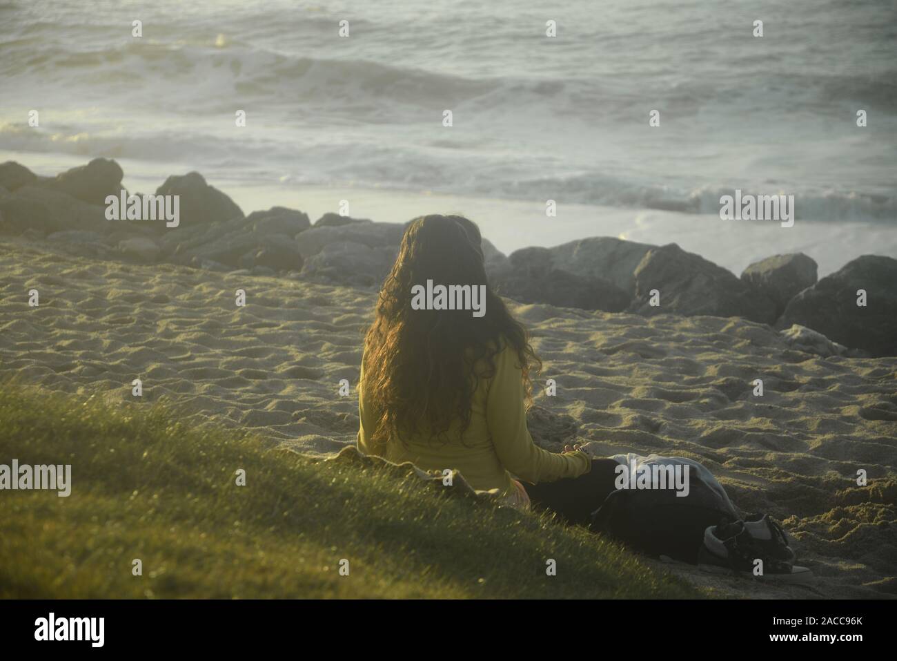 Betrachtung: Eine junge Frau, die in der Meditation mit Blick auf den Ozean, pasakdek Stockfoto
