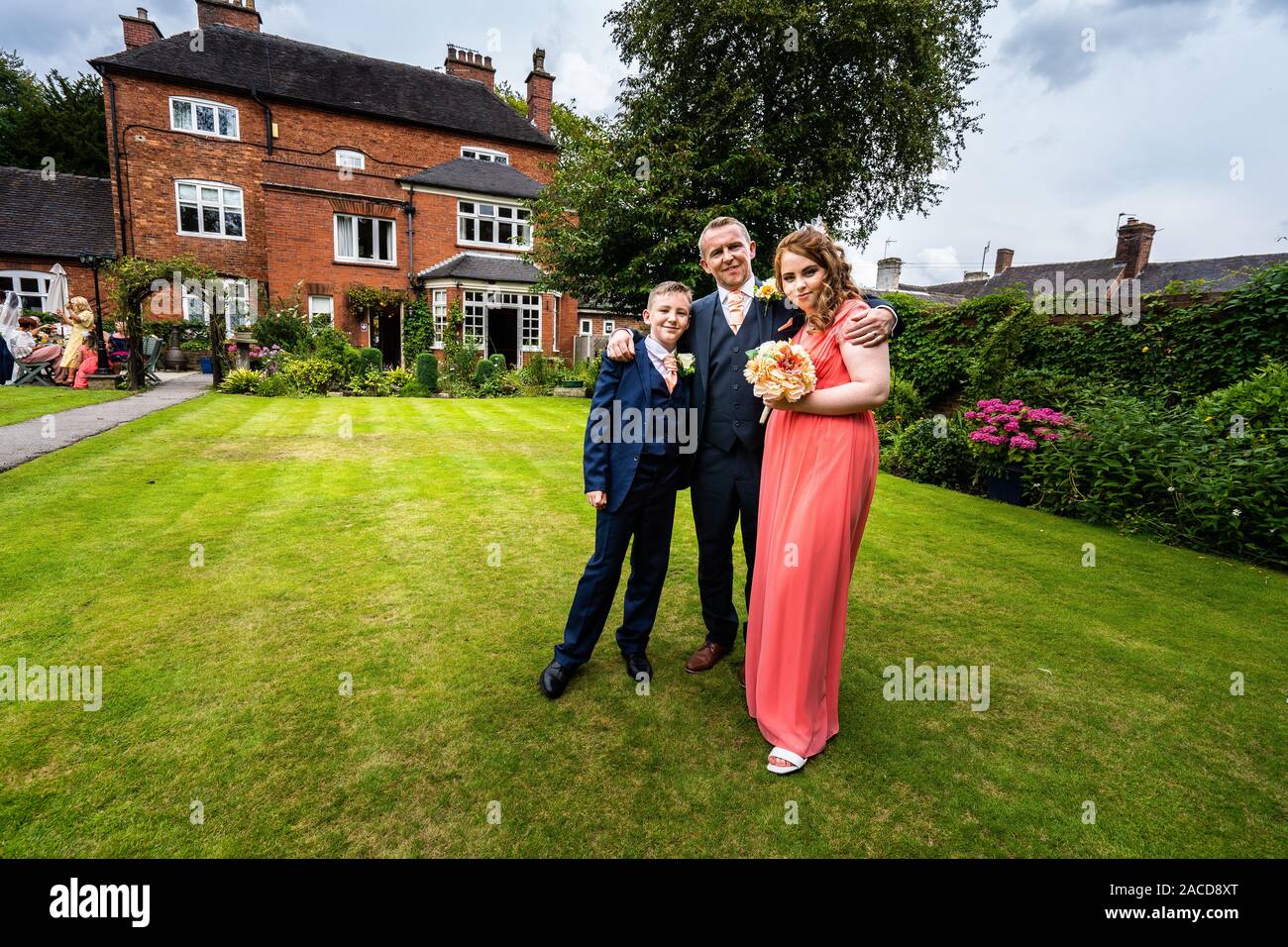 Braut, Bräutigam und Hochzeitsgäste posieren draußen für ein Foto im Manor Hotel, B&B in Cheadle, Stoke on Trent, Staffordshire, Hochzeitstag Stockfoto