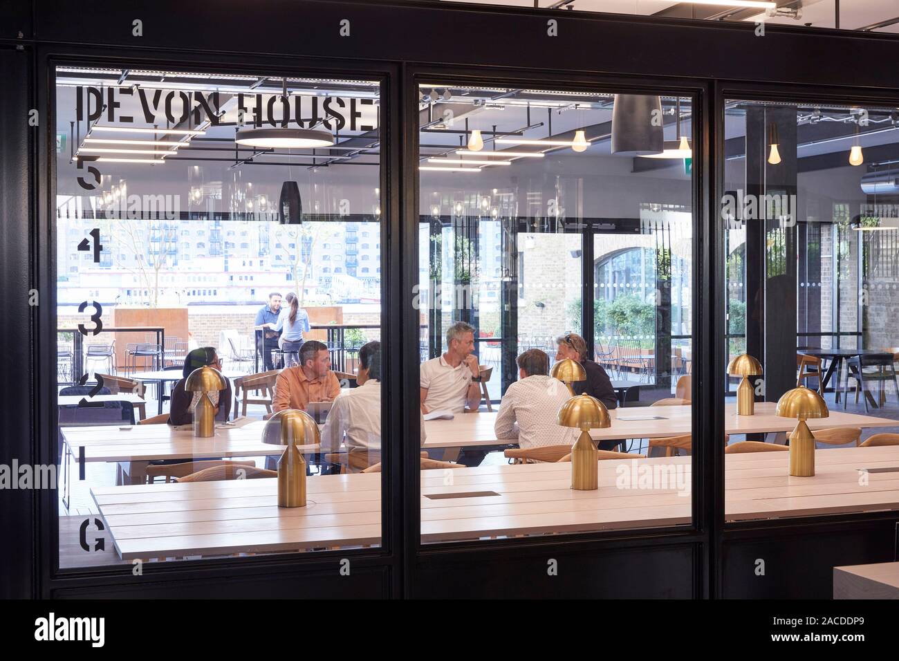 Gemeinschaftstisch im Erdgeschoss. Devon House, London, Vereinigtes Königreich. Architekt: Steif+Trevillion Architekten, 2019. Stockfoto