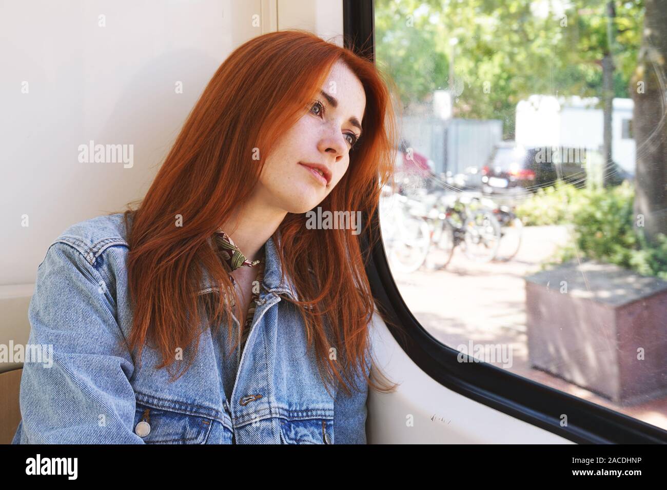 Ehrliche junge Frau in der Straßenbahn oder der U-Bahn sitzen, schauen aus dem Fenster - der öffentliche Verkehr und pendeln Konzept Stockfoto