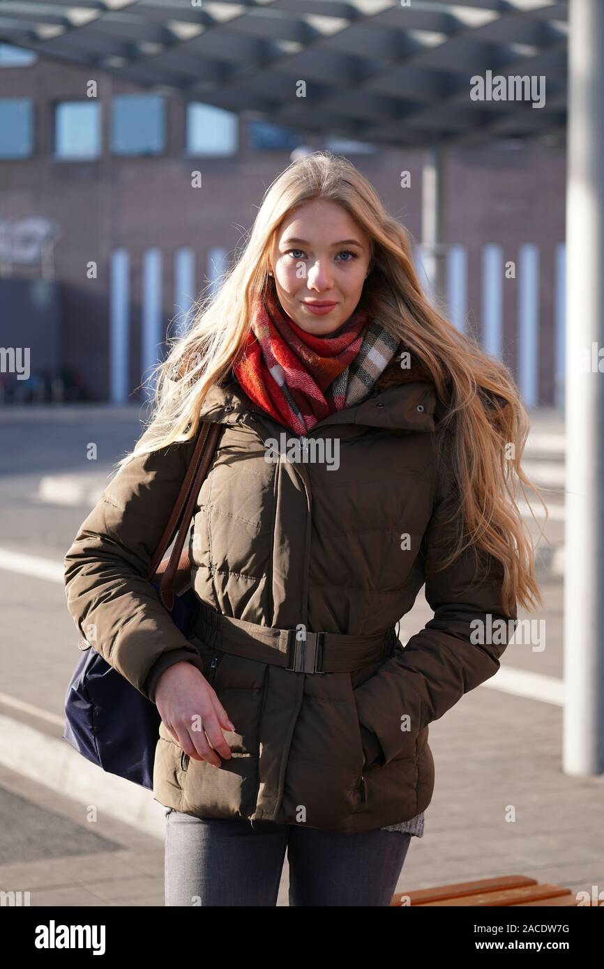 Street Style Fashion Porträt der jungen Frau an der Bushaltestelle warten an einem sonnigen Tag im Winter Stockfoto