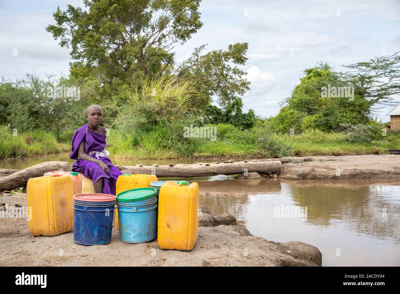 Gleichen, Tansania, 11. Juni 2019: Maasai Mädchen an der schlammigen Strom Trinkwasser zu sammeln Stockfoto