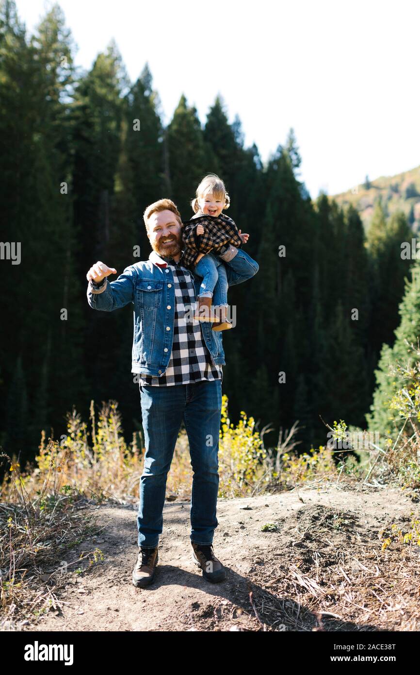 Vater trägt seine Tochter auf seinen Schultern durch Wald Stockfoto