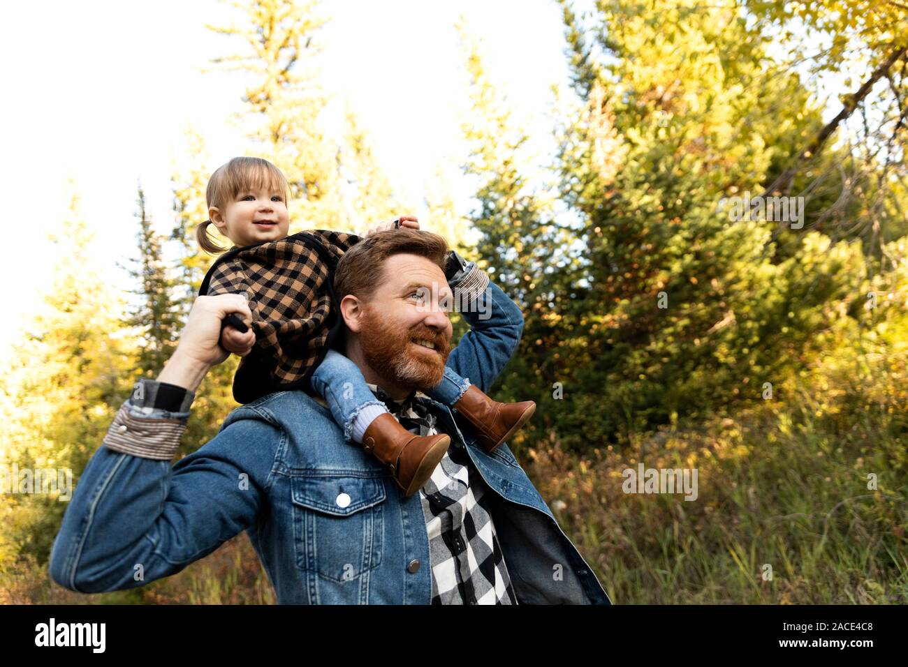 Vater trägt seine Tochter auf den Schultern im Wald Stockfoto