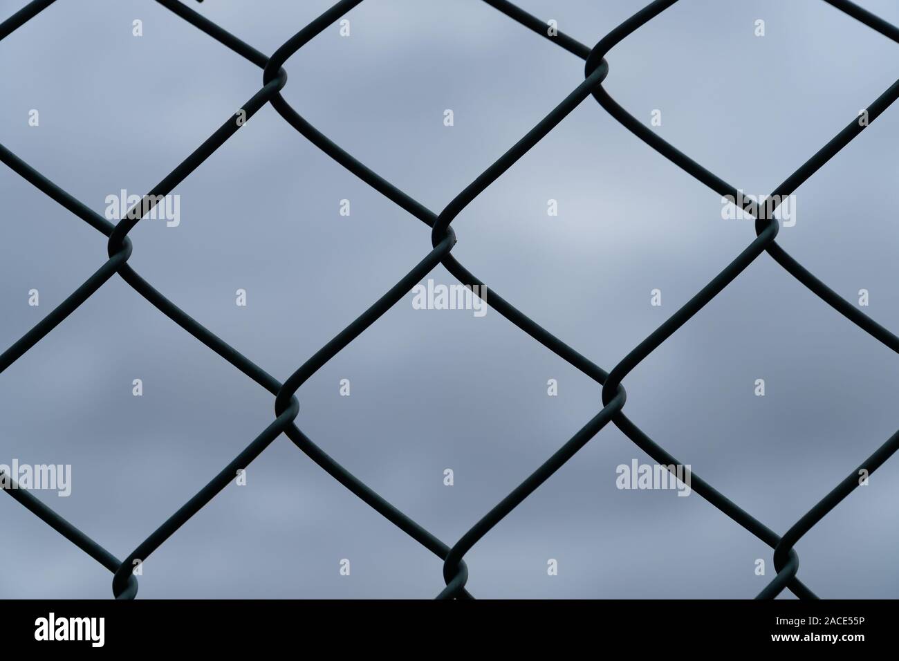 Details eines Maschendrahtzaun vor der Dunklen und bewölkter Himmel - Sicherheitskonzept Stockfoto