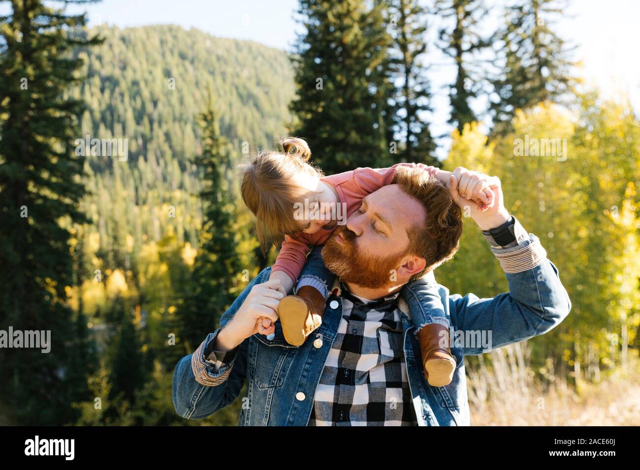 Vater trägt seine Tochter auf seinen Schultern durch Wald Stockfoto