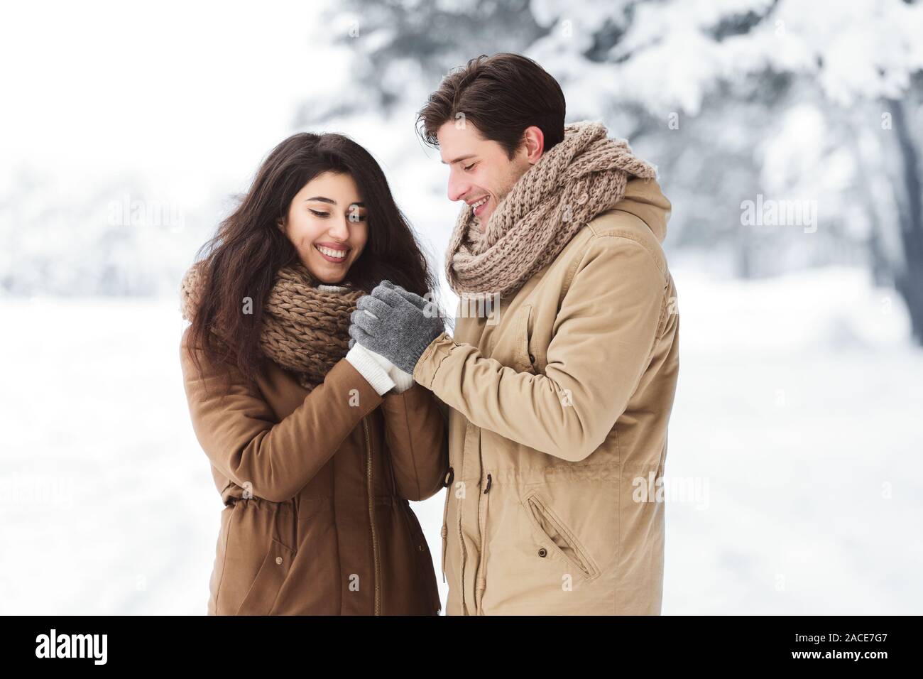 Liebevoller Ehemann der Frau die Hände reiben stehen im Winter Wald Stockfoto