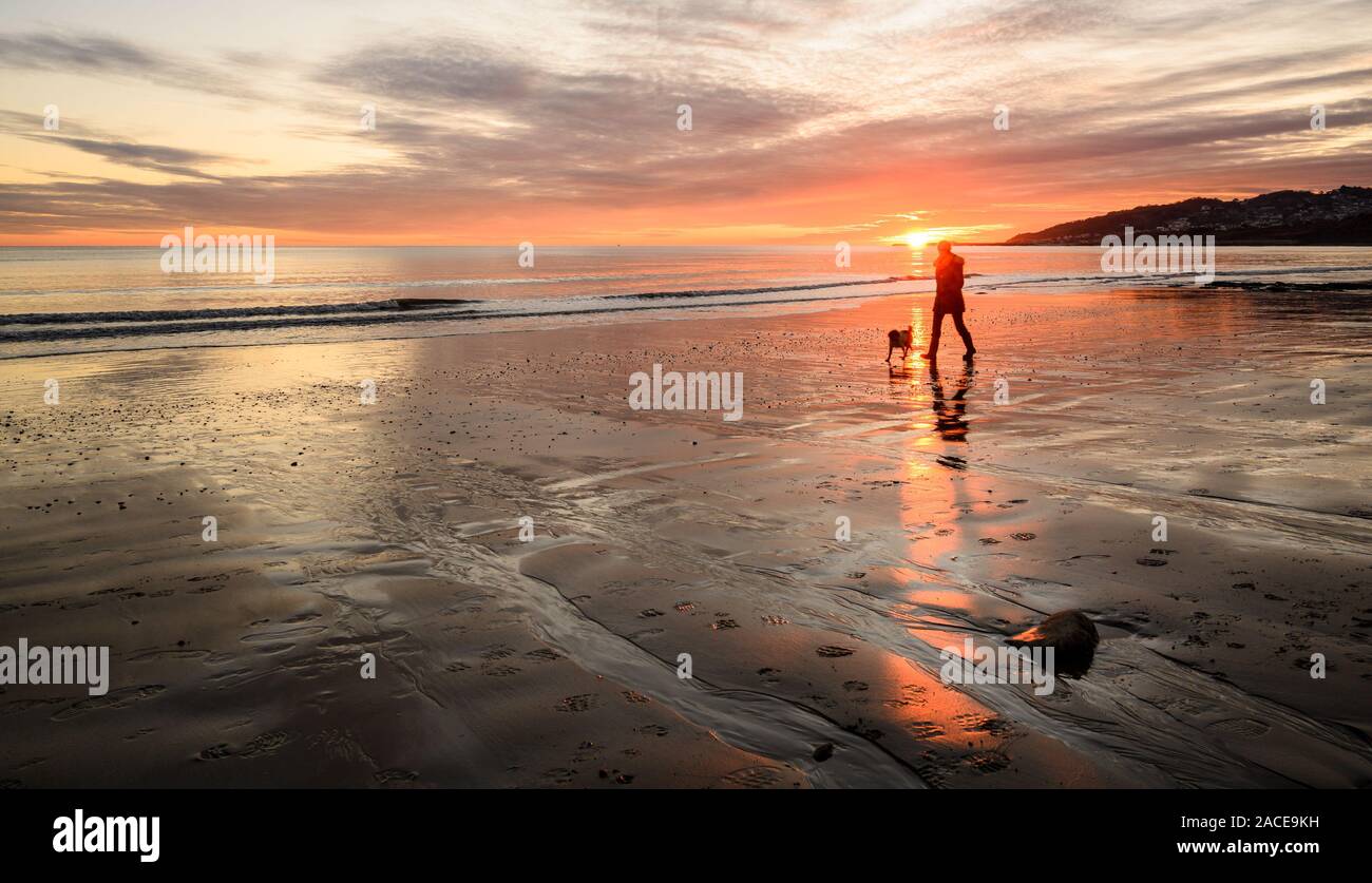 Charmouth, Dorset, Großbritannien. 2. Dezember 2019. UK Wetter: spektakuläre Farben werden im nassen Sand bei Ebbe wider, wie die Sonne über den Strand setzt bei der Küstenstadt Charmouth. Der beliebte Strand ist abgesehen von einem einsamen Person ihren Hund verlassen. Credit: Celia McMahon/Alamy Leben Nachrichten. Stockfoto