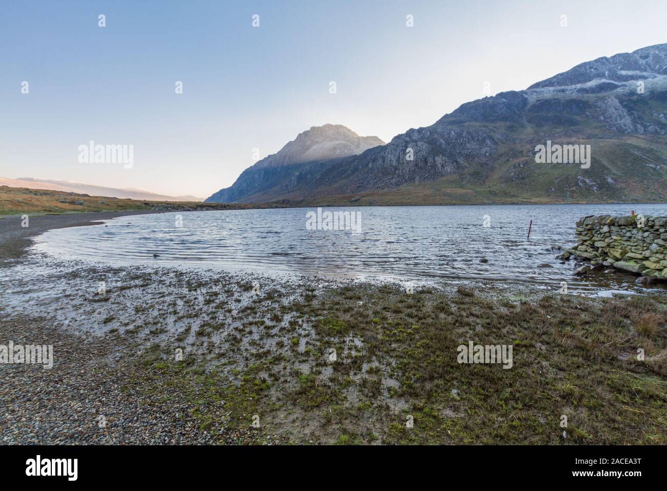 Morgen Licht auf die schneebedeckten Gipfel des Tryfan vom Ufer des Sees oder Llyn Idwal. Snowdonia National Park, Gwynedd, Wales, UK. Landschaft, Weitwinkel. Stockfoto