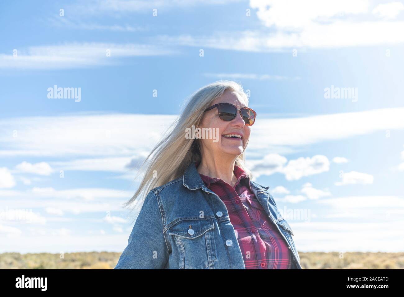 Frau trägt Sonnenbrille gegen Wolke Stockfoto