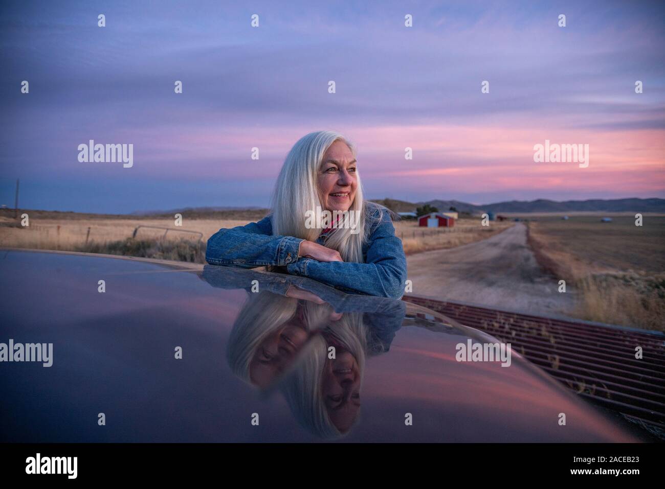 Frau, die sich bei Sonnenuntergang in Boise, Idaho, USA, auf das Auto lehnt Stockfoto