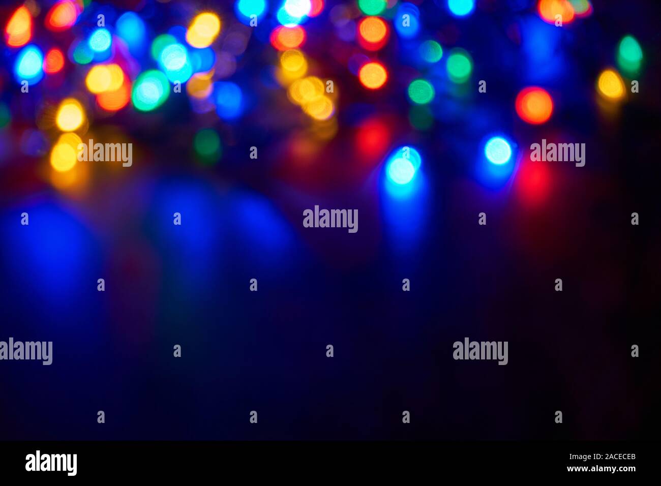Verschwommen bokeh christmas lights in Blau, Rot, Gelb, Orange und Grün auf dunklem Hintergrund Stockfoto