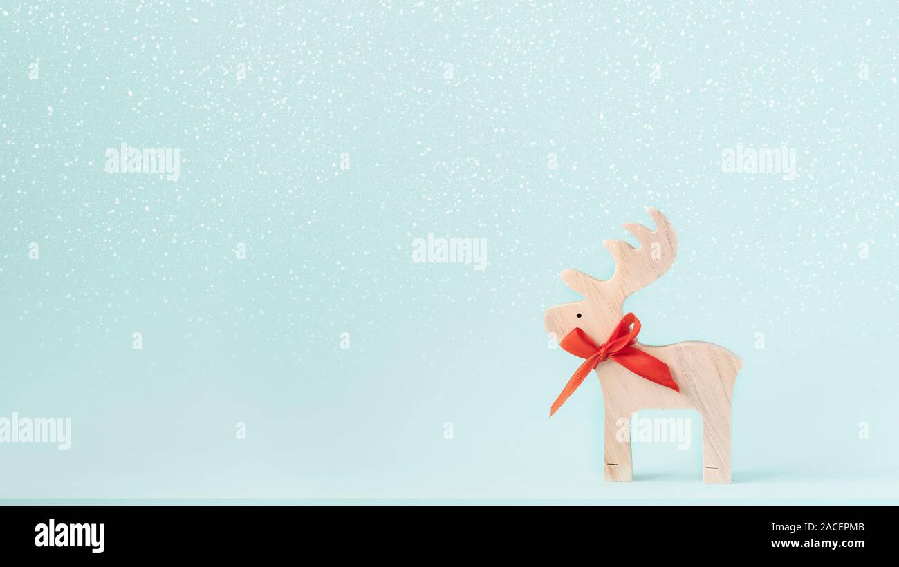 weihnachten oder Neujahr minimaler Kopierraum Hintergrund. Das hölzerne Rentier auf Schnee und mintfarbenen Hintergrund. Stockfoto