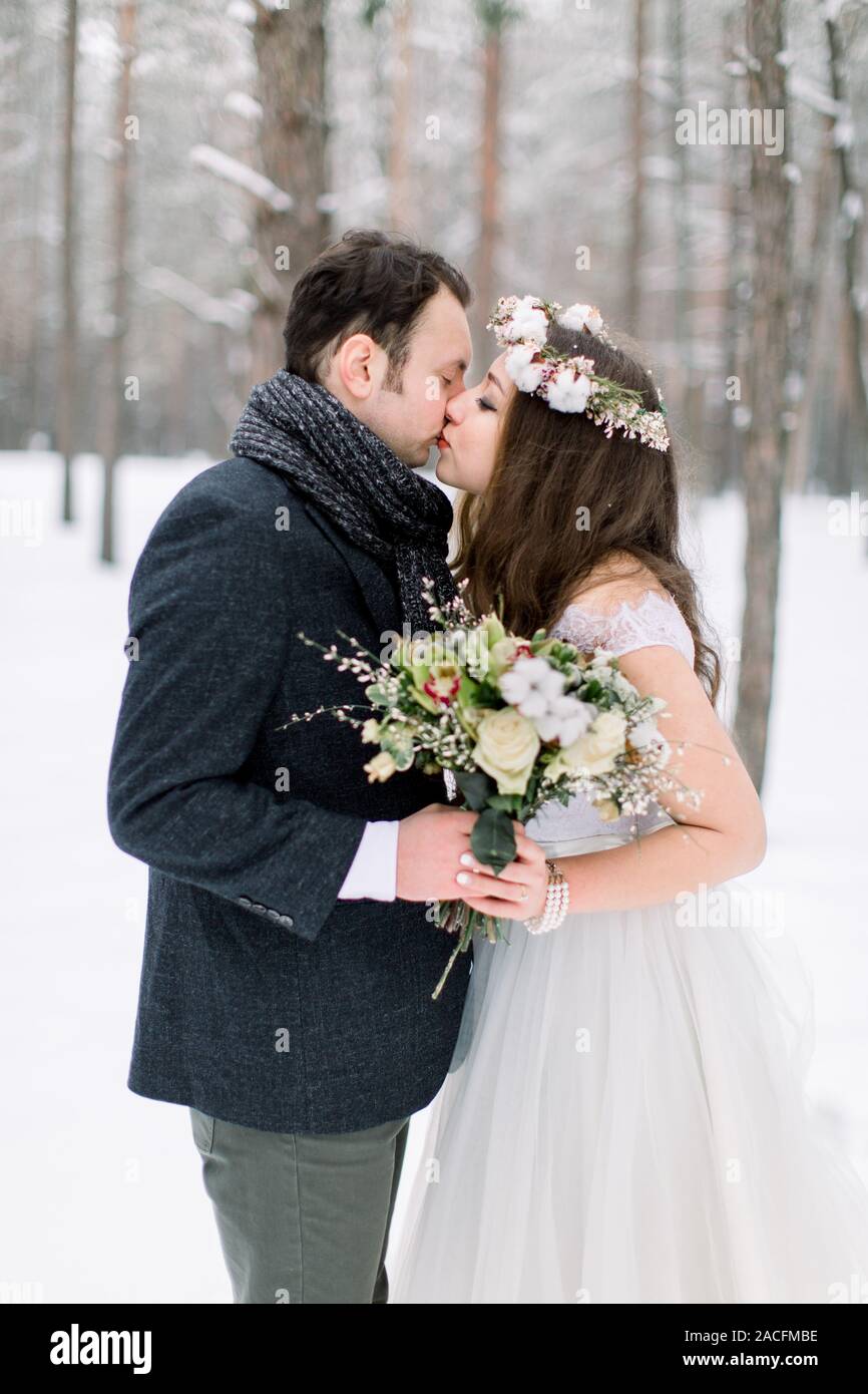 Hübsche junge Braut in Kranz auf dem Kopf küssen ihr schöner Bräutigam, ein  Wintermärchen. Winter Hochzeit im Wald Stockfotografie - Alamy