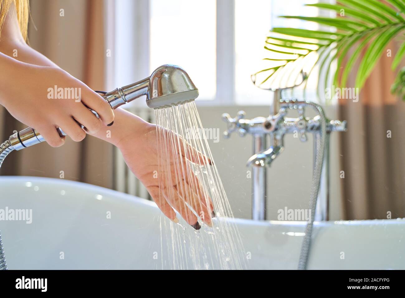 Wasser aus der Dusche auf die Hände des Mädchens. Auf einem blauen  Hintergrund. Frau prüft die Temperatur des Wassers im Hintergrund der  Badezimmer Stockfotografie - Alamy