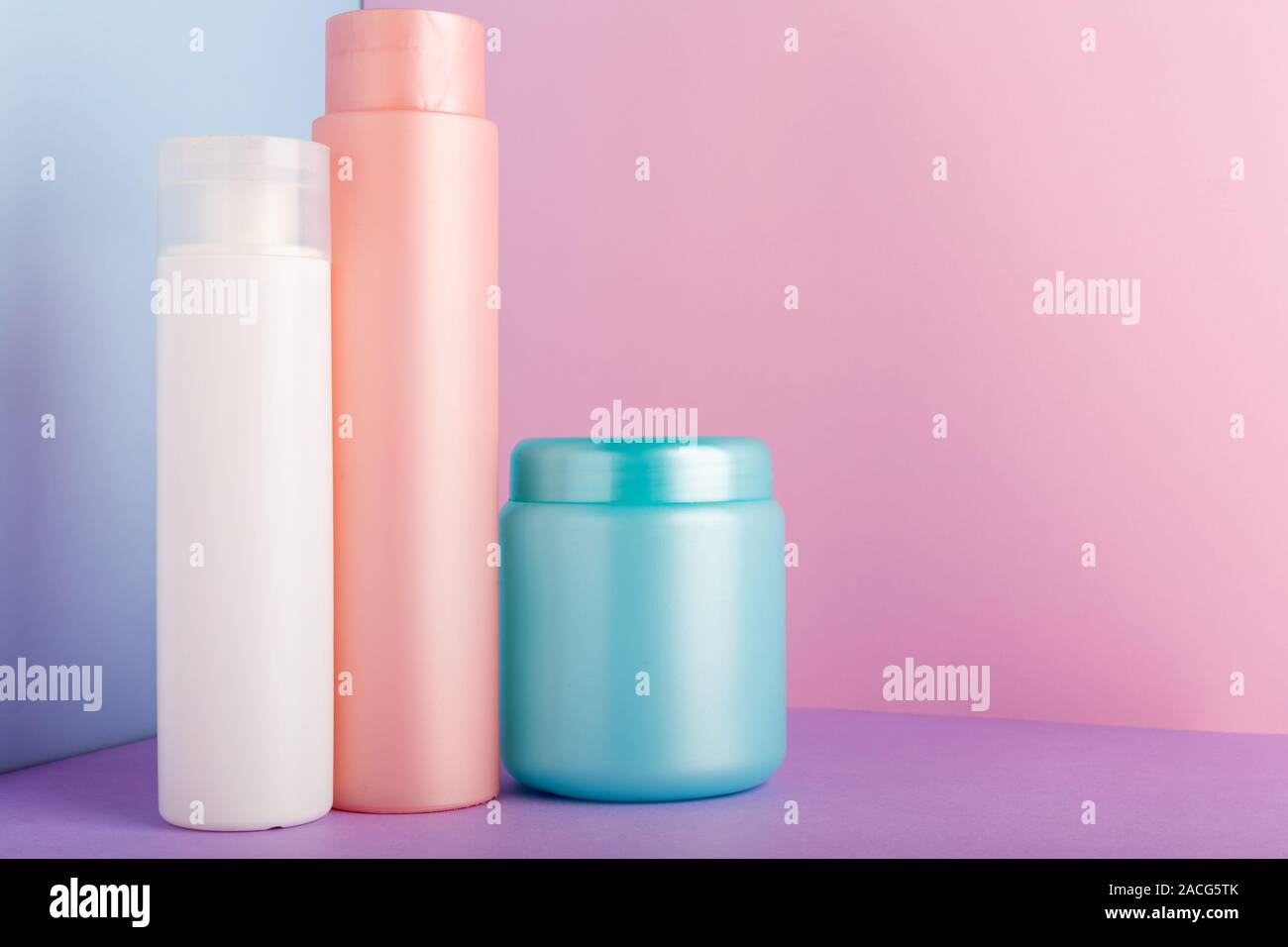 Satz von kosmetischen Produkten auf rosa Hintergrund. Kosmetik Paket Sammlung für Shampoo, Maske, Conditioner, Duschgel. Rosa, Weiß, Blau Kunststoff Flaschen Stockfoto