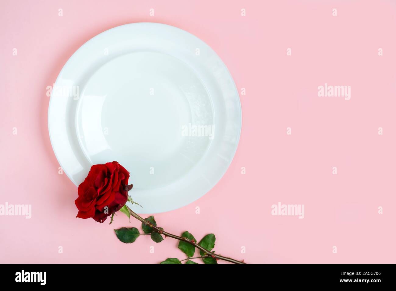 Romantisch gedeckten Tisch für Valentines Tag oder Abendessen Datum Feier Hochzeit. Valentines Tag Konzept mit rote Rose Bud White Platten auf Pastell rosa Tischdecke Hintergrund. Flach, Ansicht von oben kopieren. Stockfoto