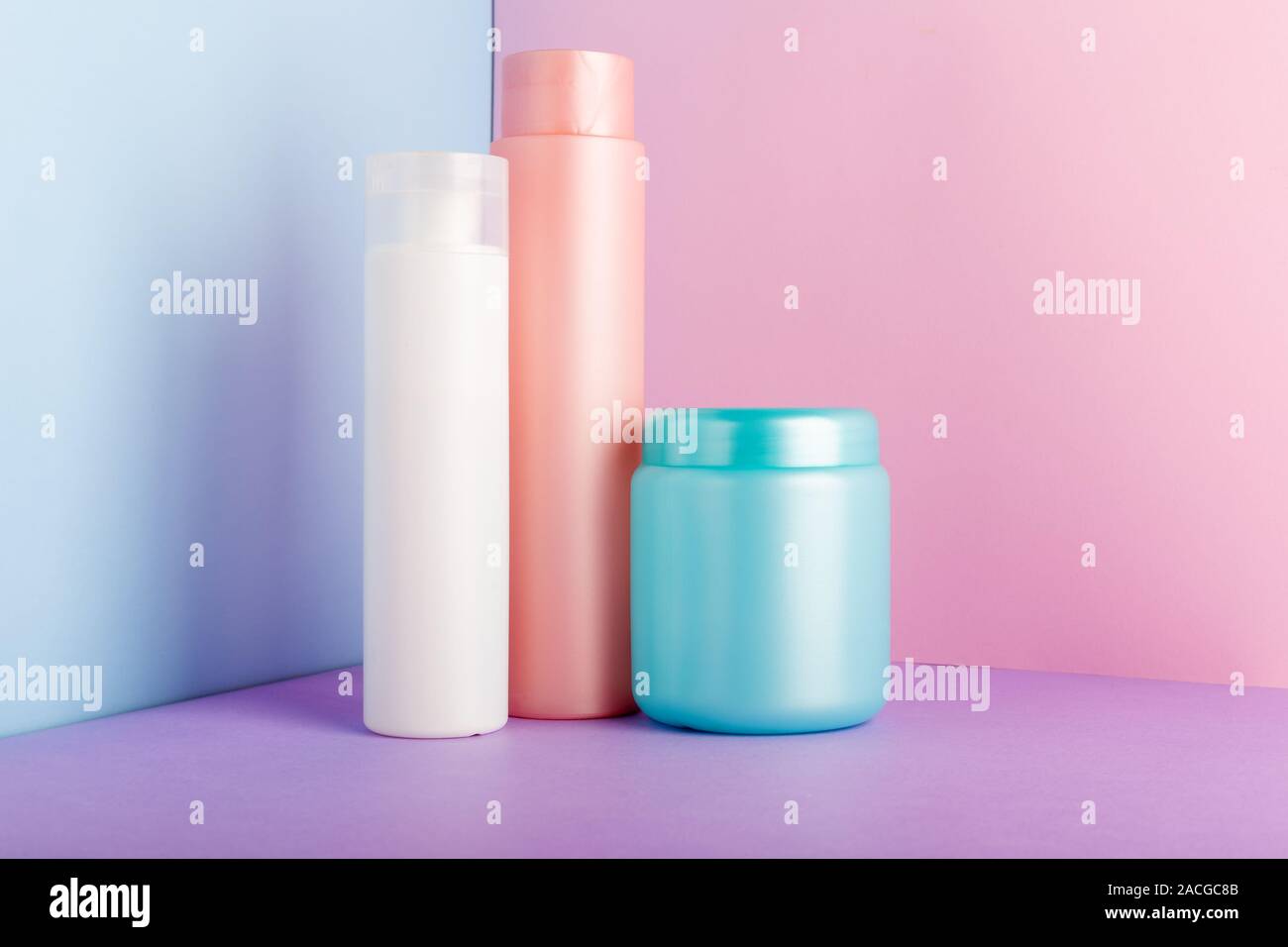 Satz von kosmetischen Produkten auf rosa Hintergrund. Kosmetik Paket Sammlung für Shampoo, Maske, Conditioner, Duschgel. Rosa, Weiß, Blau Kunststoff Flaschen Stockfoto