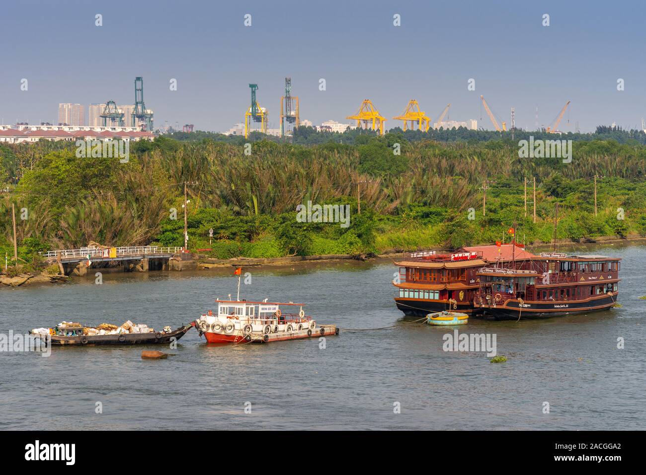 Ho Chi Minh City, Vietnam - März 13, 2019: braun Holz- touristische Restaurant Boote und kleine Schiffe auf blau-grau Wasser mit grünen Gürtel teilweise Ausblenden y Stockfoto