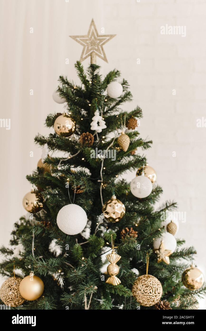 Der obere Rand der Weihnachten künstlichen Baum stehend zu Hause. Beige golden glänzenden Stern an der Spitze des Baumes. Dekorieren ein Weihnachtsbaum mit beige, gold Stockfotografie