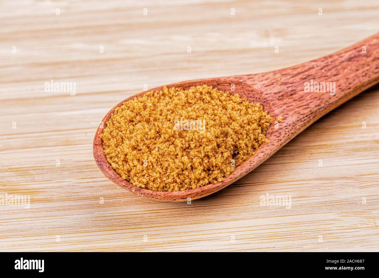 Löffel aus Holz, voll von süßen braunen Zucker auf einer hölzernen Hintergrund Stockfoto