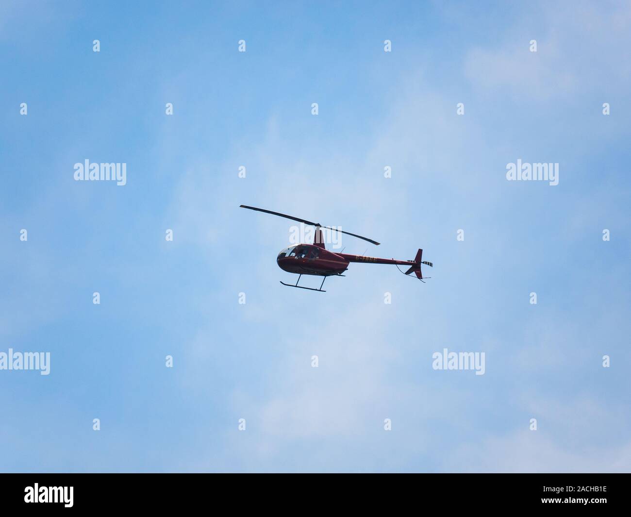 Robinson R44 roter Hubschrauber im Flug. Stockfoto