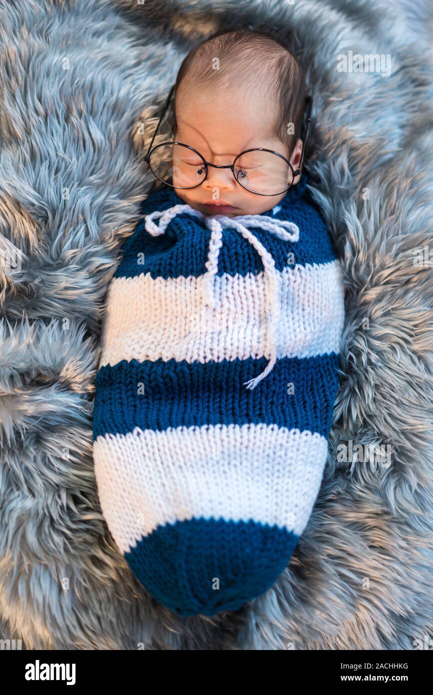 Neugeborenes Baby boy Brille Schlaf- und Gepuckte in einem Stricken wrap  auf einem Bett Stockfotografie - Alamy