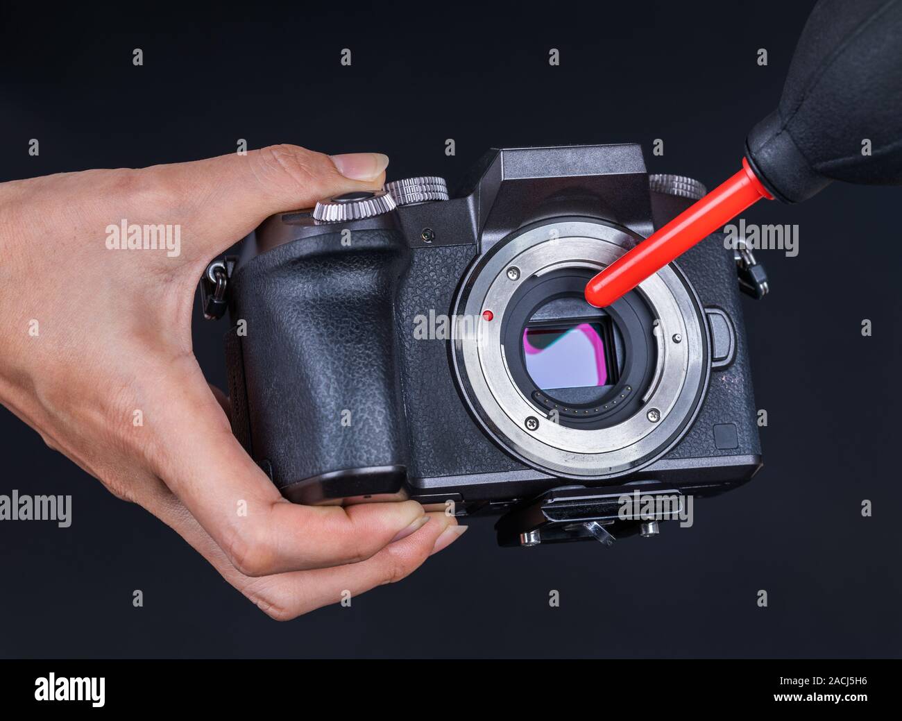 Hand mit Gebläse zur Reinigung Staub auf den Sensor einer Kamera Stockfoto