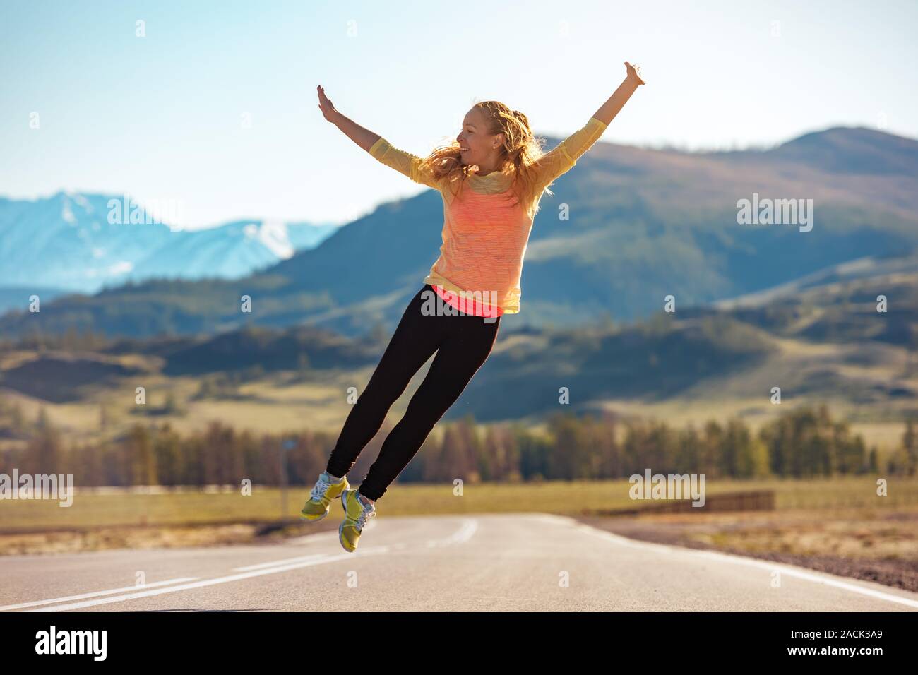 Gerne sportliche Mädchen springt auf geraden Mountain Road Stockfoto