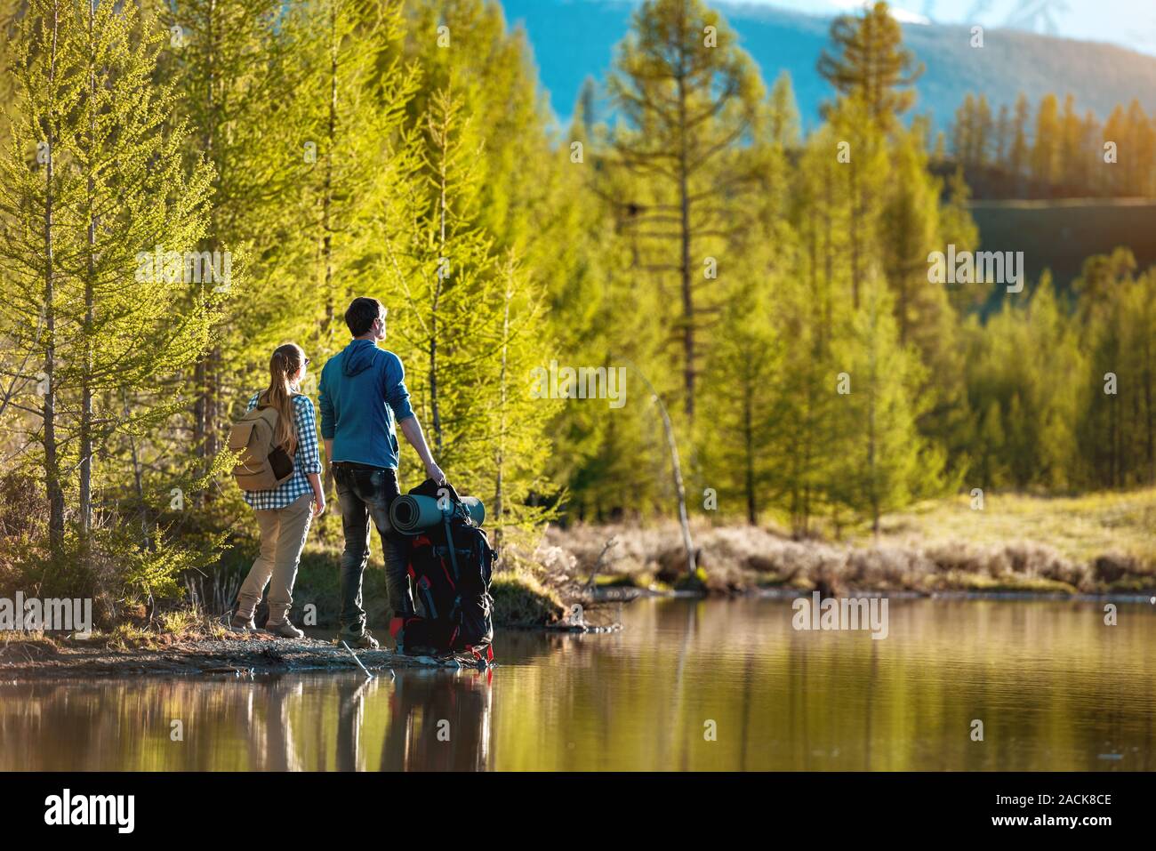 Zwei Wanderer mit Rucksack stehen und entspannen in der Nähe von Mountain Lake Stockfoto
