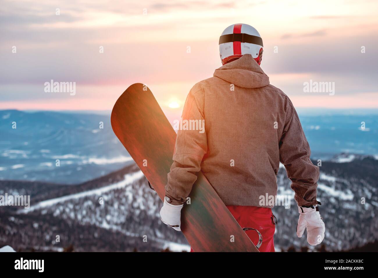 Snowboarder steht mit Snowboard in die Hände gegen Sonnenuntergang und Berge Stockfoto