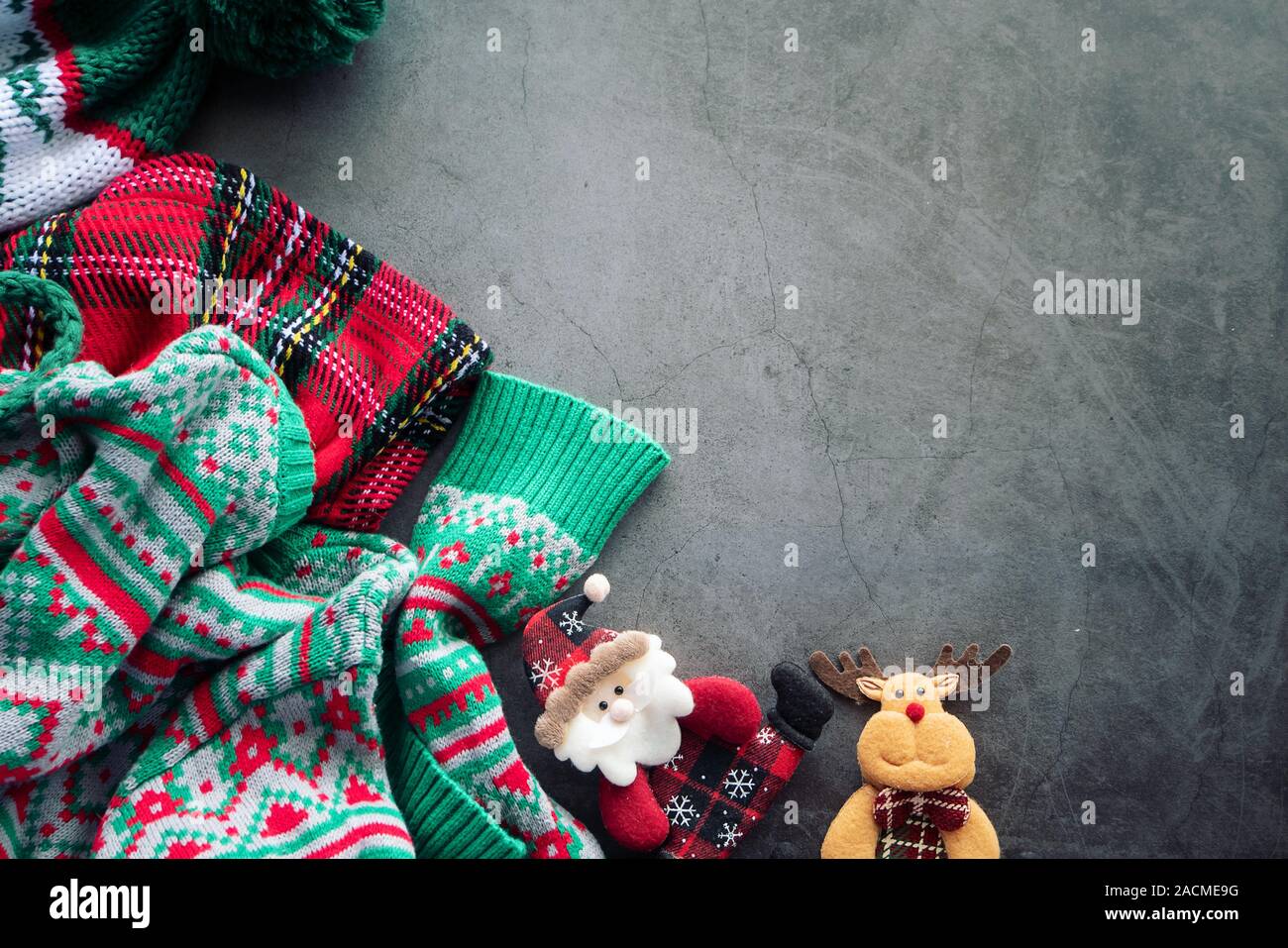 Grünen Pullover und rot Scotch decke Verlegung auf dem Zement Hintergrund mit einem Santa Claus Doll und ein Rentier für Weihnachten Ornament mit Kopie Raum Stockfoto