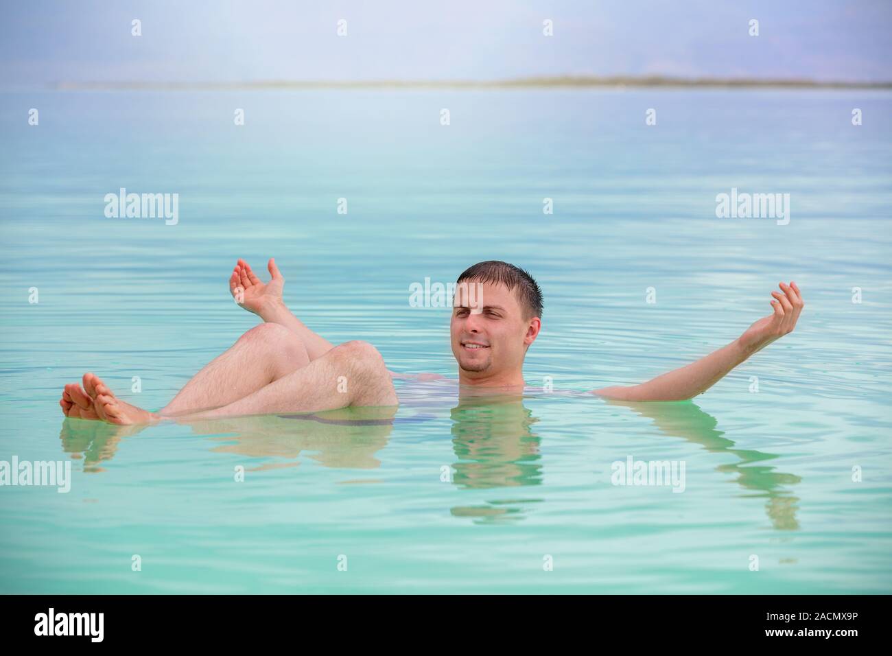 Mann mit den Händen in der Luft schwimmen im Toten Meer. Spa verfahren. Sommer, Urlaub, Reise-Konzept. Szene aus dem Toten Meer Stockfoto