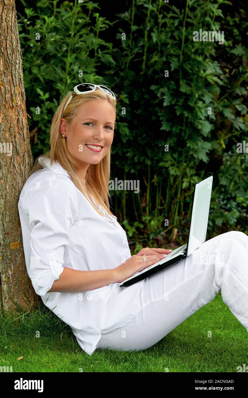 Frau mit Laptop im Garten Stockfoto