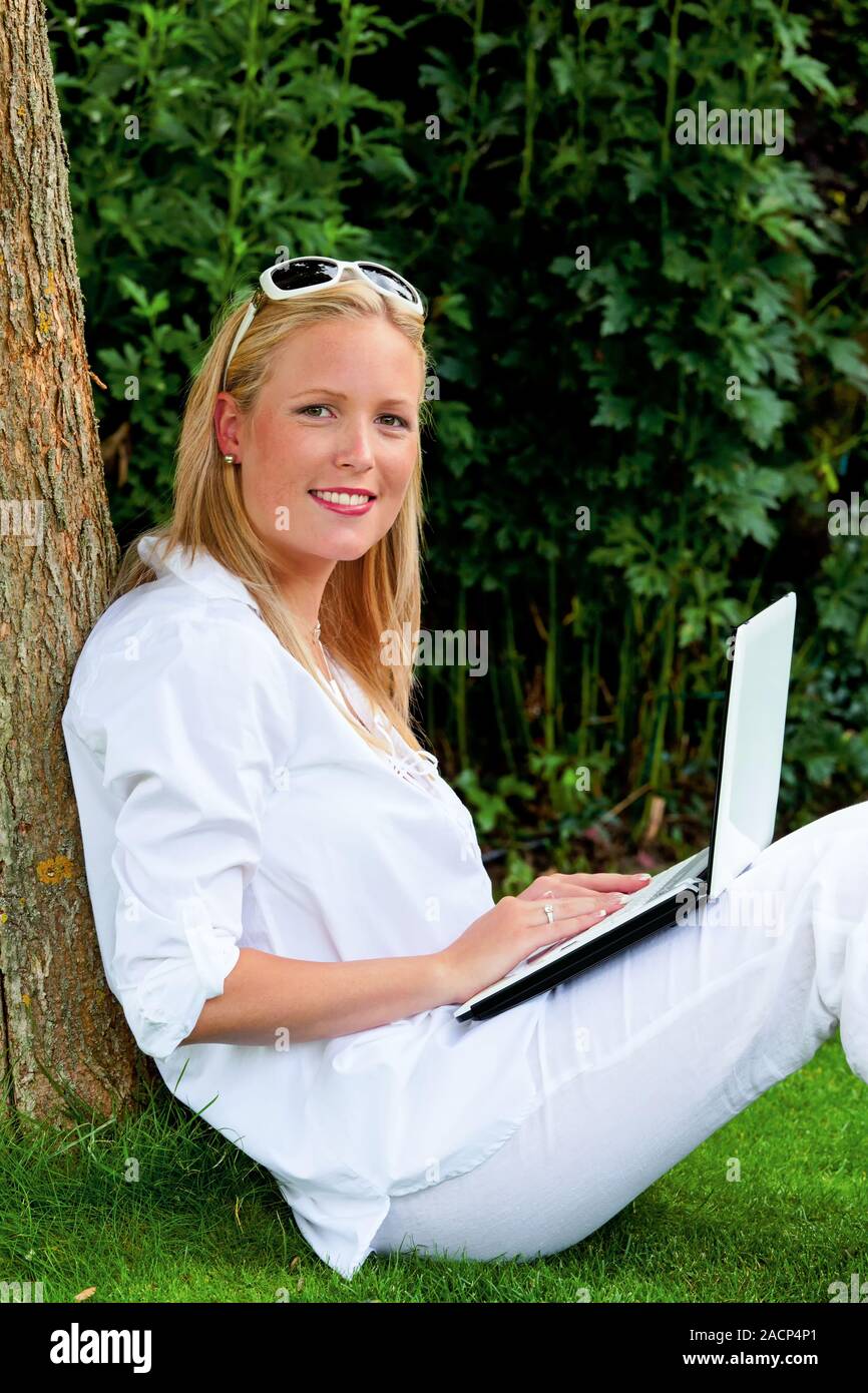 Frau mit Laptop im Garten Stockfoto