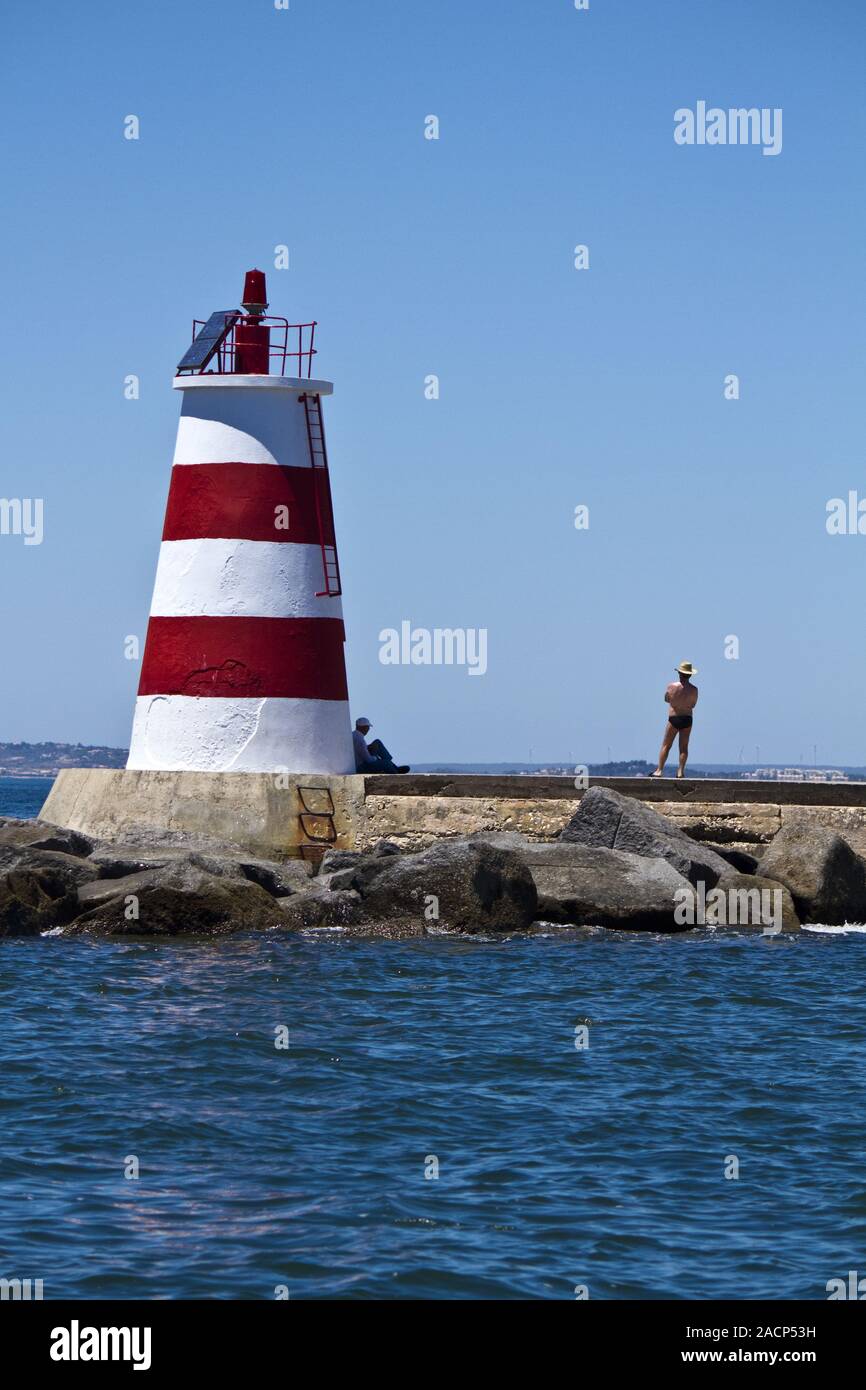 Zwei Person das Meer bewundern neben einem kleinen Leuchtturm Stockfoto