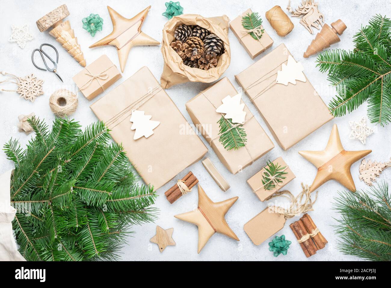 Null Abfall umweltfreundliche Weihnachten Hintergrund. Xmas Tree Branches in Baumwolle, wiederverwendbare Tasche, präsentiert in braunes Papier, kiefernzapfen Tags hessische Cinnamon Sticks für die Dekoration. Ansicht von oben, selektiver Fokus Stockfoto