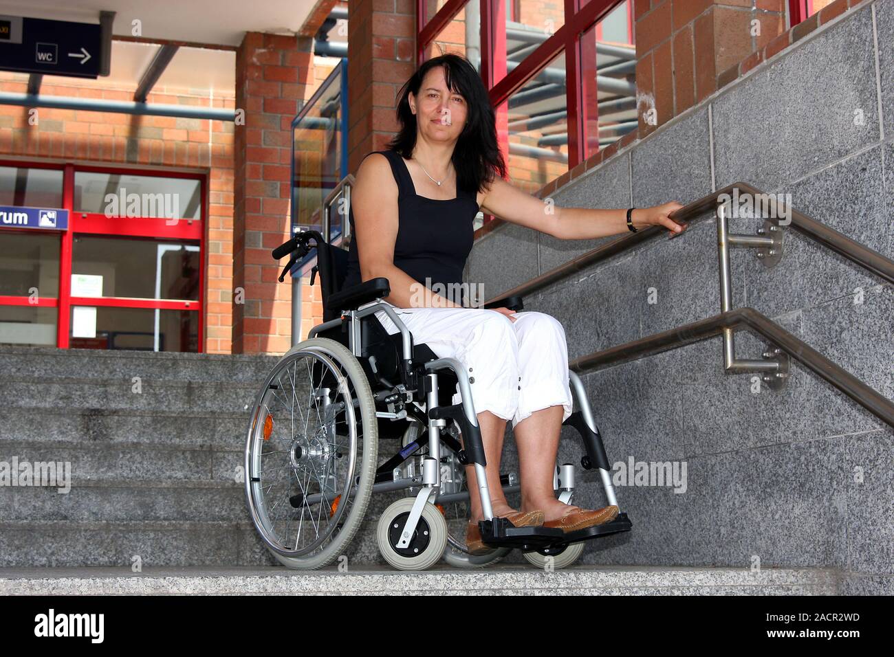 Behinderte Frau in einem Rollstuhl, Alltag in der Stadt Stockfoto