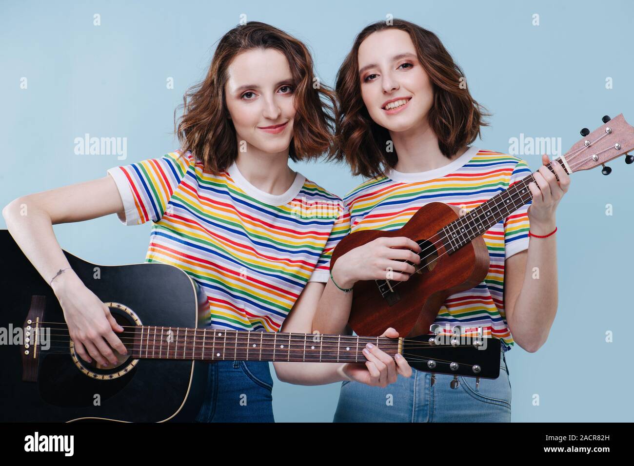 Zwei Zwillingsschwestern spielen an der Gitarre und Ukulele zusammen Stockfoto