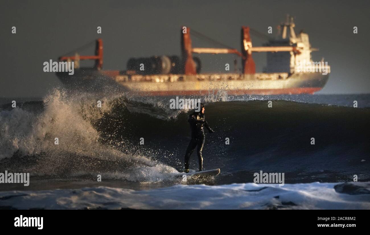 Ein Surfer reitet eine Welle vor der Küste in Tynemouth, Northumberland. Stockfoto