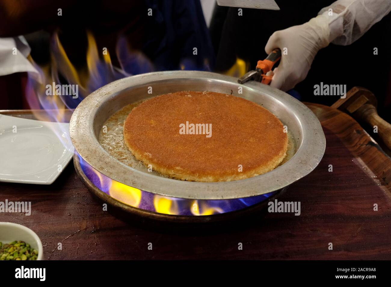 Kellner serviert eine siniyyeh (Fach) der Kanafeh einer traditionellen nahöstlichen Dessert mit dünnen Nudeln - wie Gebäck, oder alternativ, feinen Grieß Teig, in süße getränkt, Zucker-Sirup, und in der Regel mit Käse geschichtet, in Hatay Medeniyetler Sofrasi Restaurant serviert authentische türkische Küche in Istiklal Caddesi einer der berühmtesten Alleen in Istanbul, Türkei Stockfoto