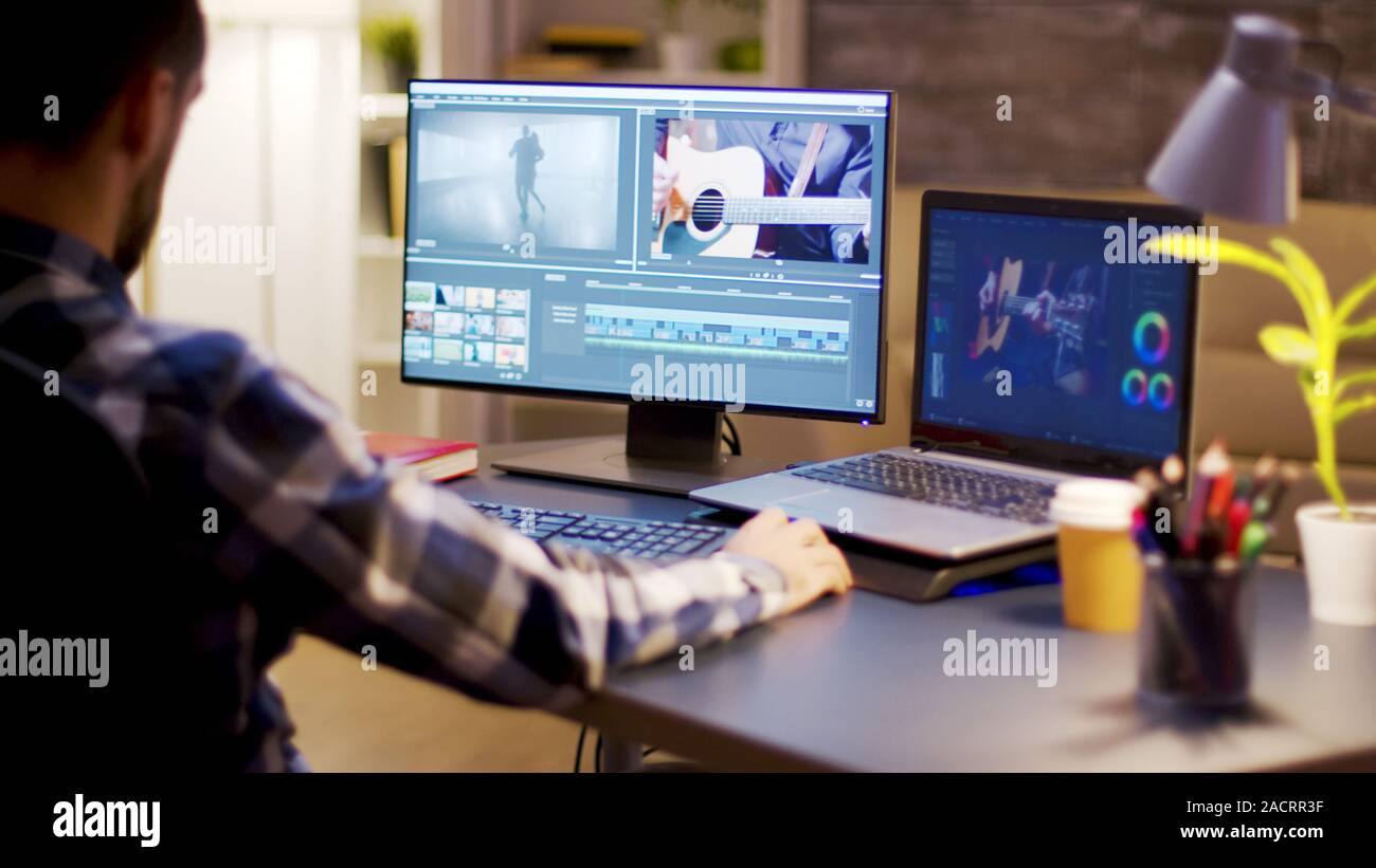 Content Creator mit moderner Software für Video Post Produktion im Büro zu Hause während der Nacht. Stockfoto