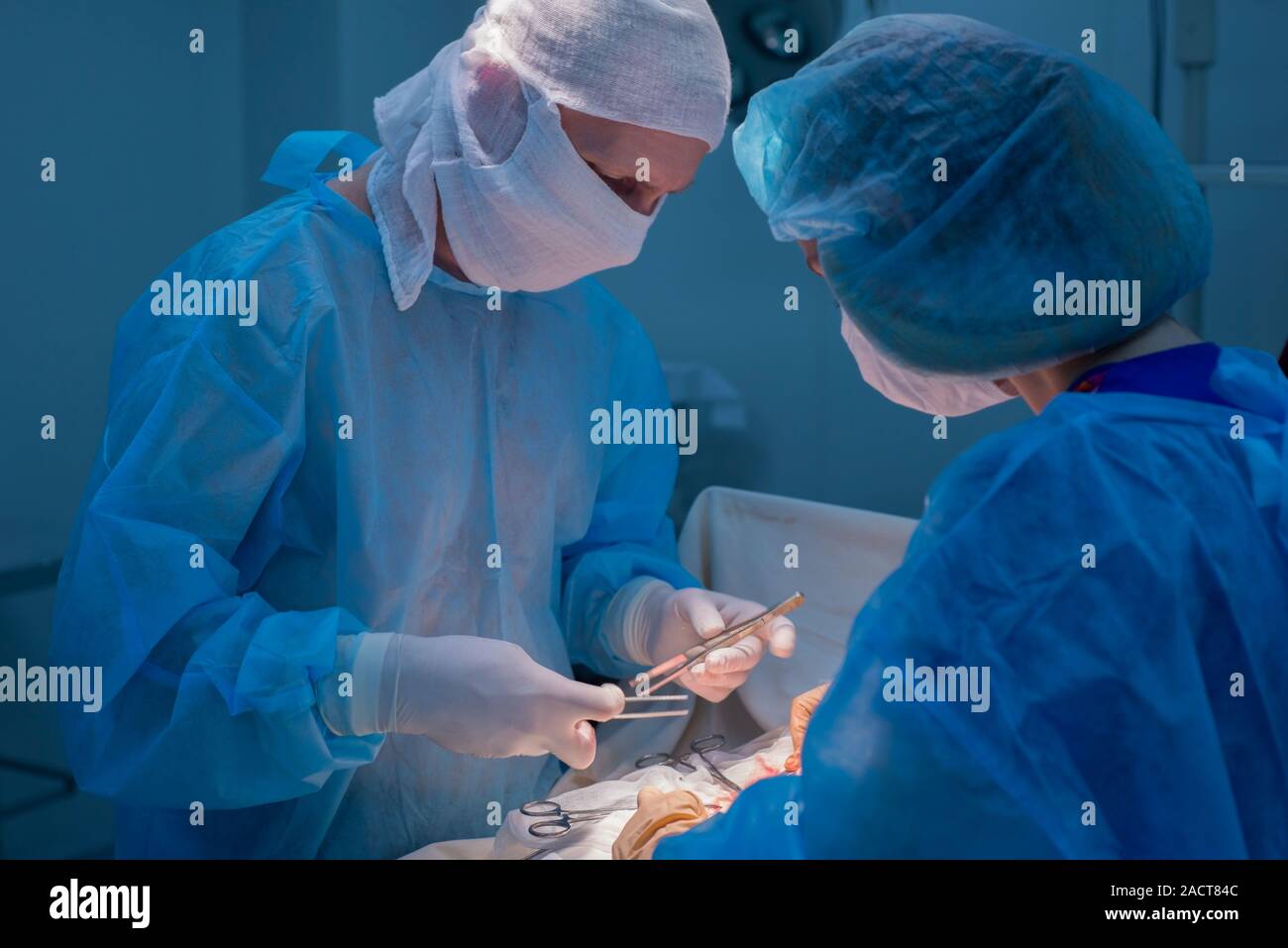 Chirurgen Kinder urologische Operationen durchführen. Ein Mann und eine Frau in einer Maske und einem blauen sterile Mantel in den Operationssaal. Ein Team von Chirurgen ist Co Stockfoto